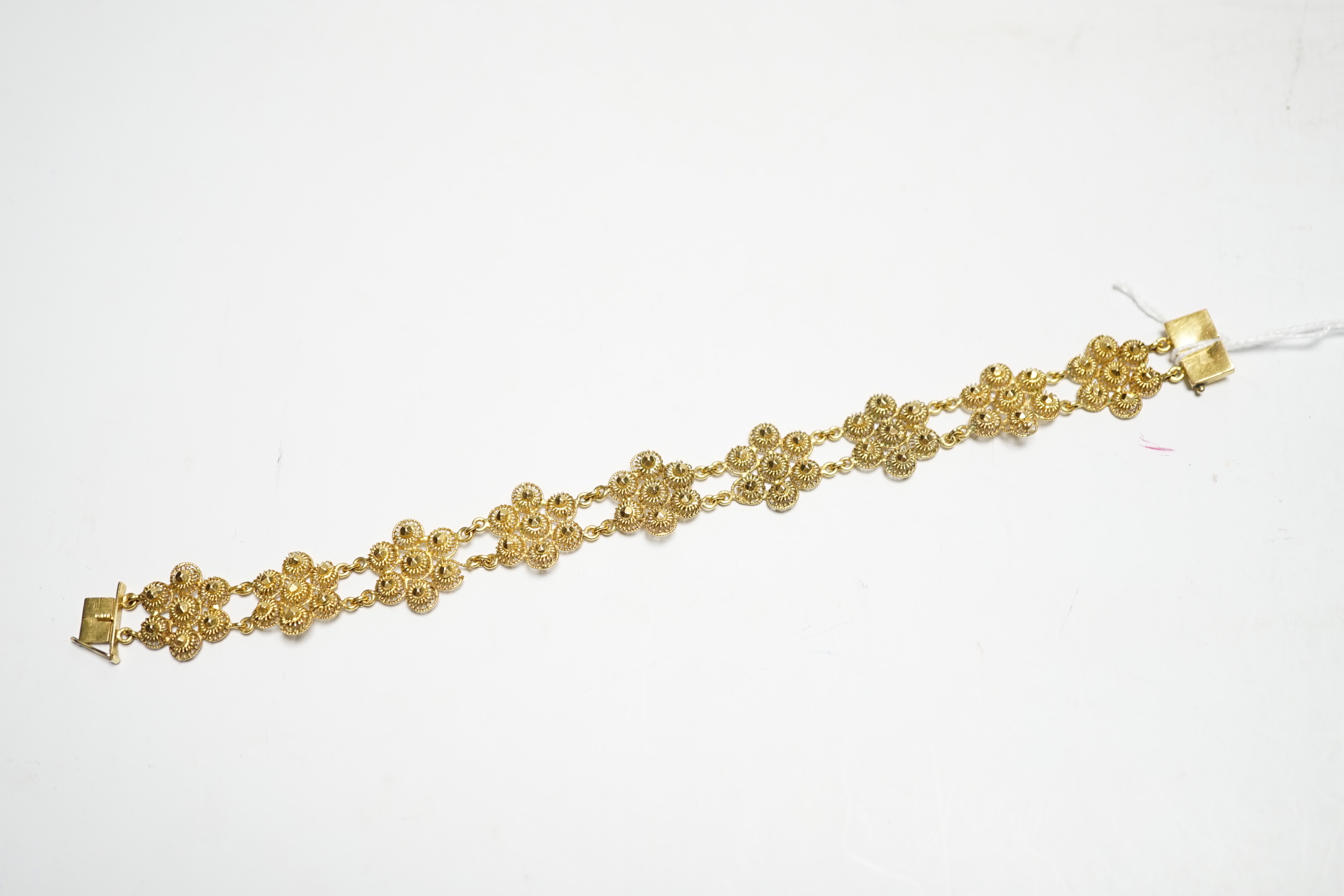 A yellow metal 'bright cut engraved' flower head link bracelet, 16cm, 14.7 grams.